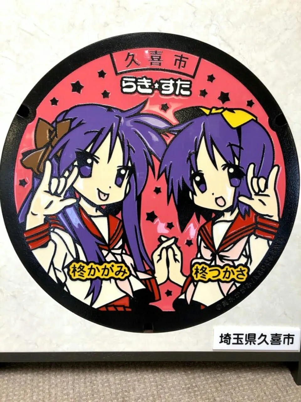 Latar Lucky Star Akan Menambahkan Tutup Lubang Got Bergambar Kagami dan Tsukasa Hiiragi